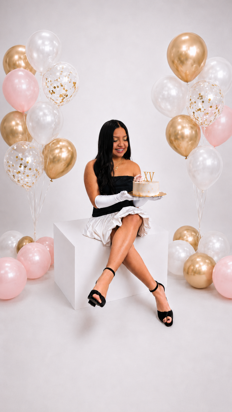Melany Sofia sosteniendo su pastel de XV años entre globos rosas y champagne